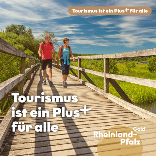Tourismus ist ein Plus für alle Kampagnenmotiv Tourismus ist ein Plus für alle: Zwei Personen wandern über einen Holzsteg durch eine grüne Landschaft.