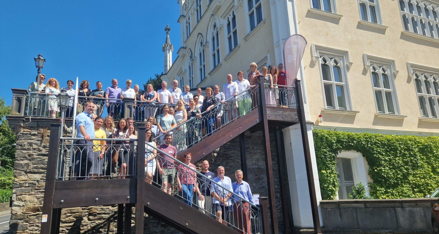 20-30 Personen auf einer Stahltreppe beim Geschäftsfeldübergreifenden Netzwerktreffen der Rheinland-Pfalz Tourismus GmbH auf Schloss Sayn​