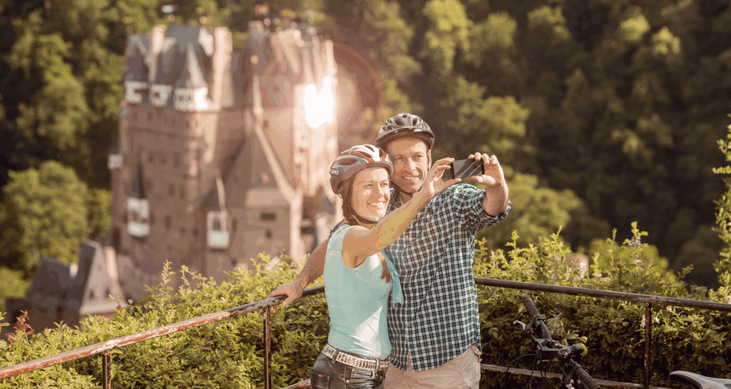 Ein Mann und eine Frau machhen ein Selfie vor Burg Eltz – zur Illustration des Handlungsfeldes Digitalisierung.