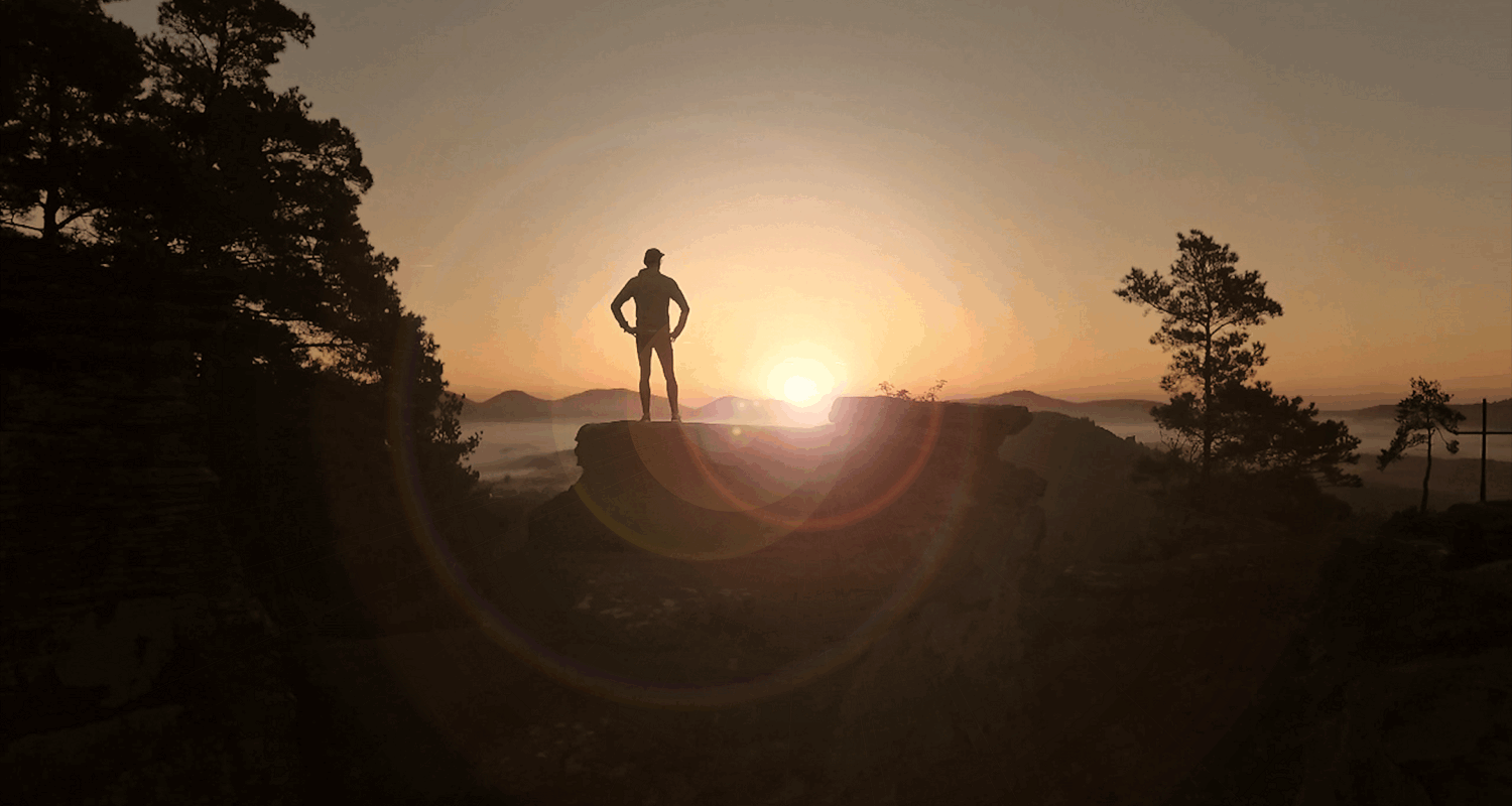 Ein Mensch auf einem Felsen blickt in den Sonnenaufgang – zur Illustration des Handlungsfeldes Profilierung und Innovation